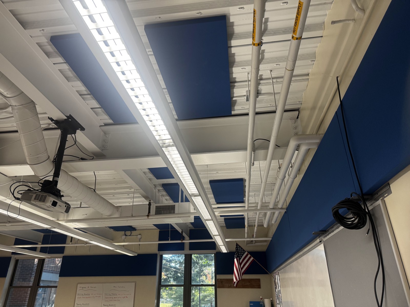 Two-inch fabric-wrapped acoustic panels installed between the ceiling beams