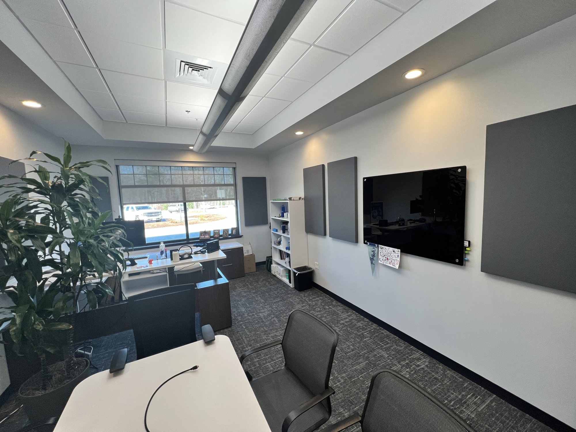 Two-inch gray fabric-wrapped acoustic panels arranged around a wall-mounted display in the Lenze America office
