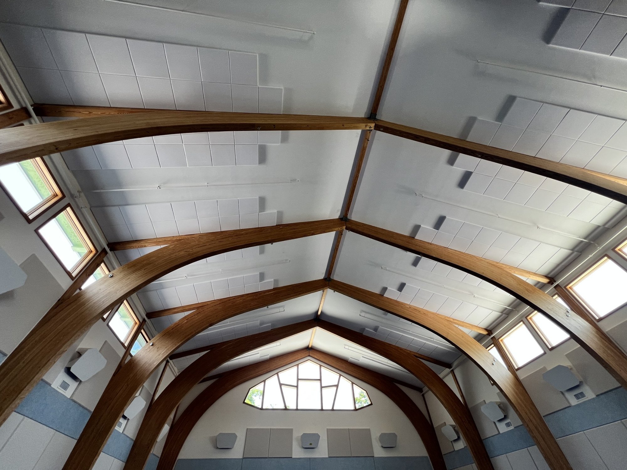 Two-inch melamine acoustic foam panels bonded to the vaulted gymnasium ceiling between glulam arches at Triform Camphill Community