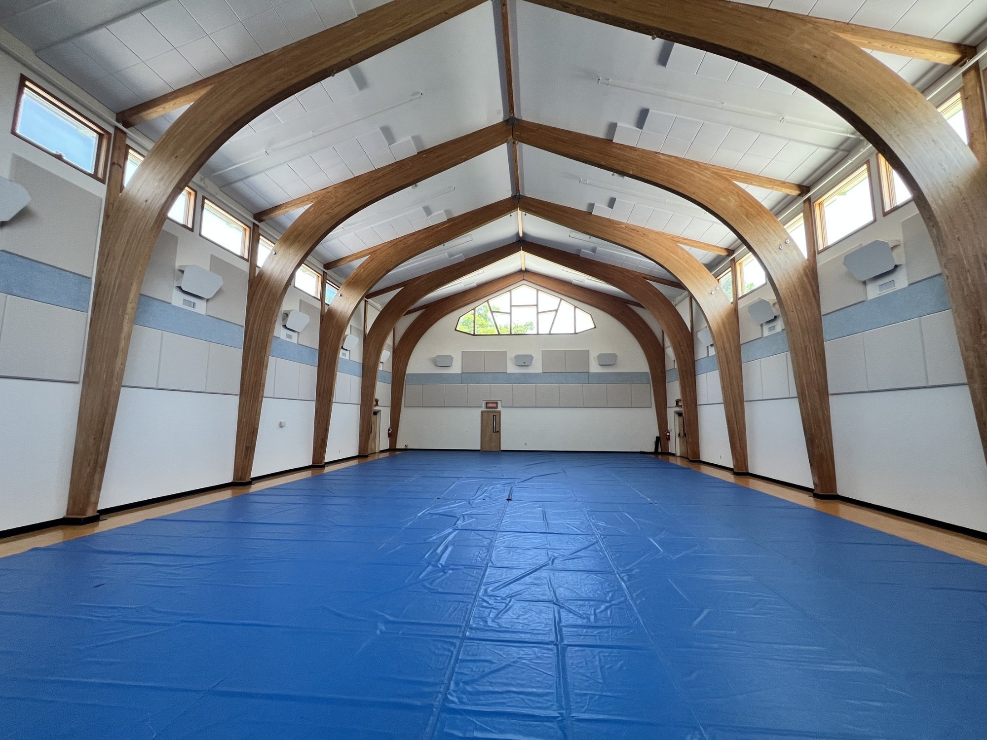 Triform Camphill Community gymnasium in Hudson NY after acoustic treatment, with foam ceiling panels between glulam timber arches
