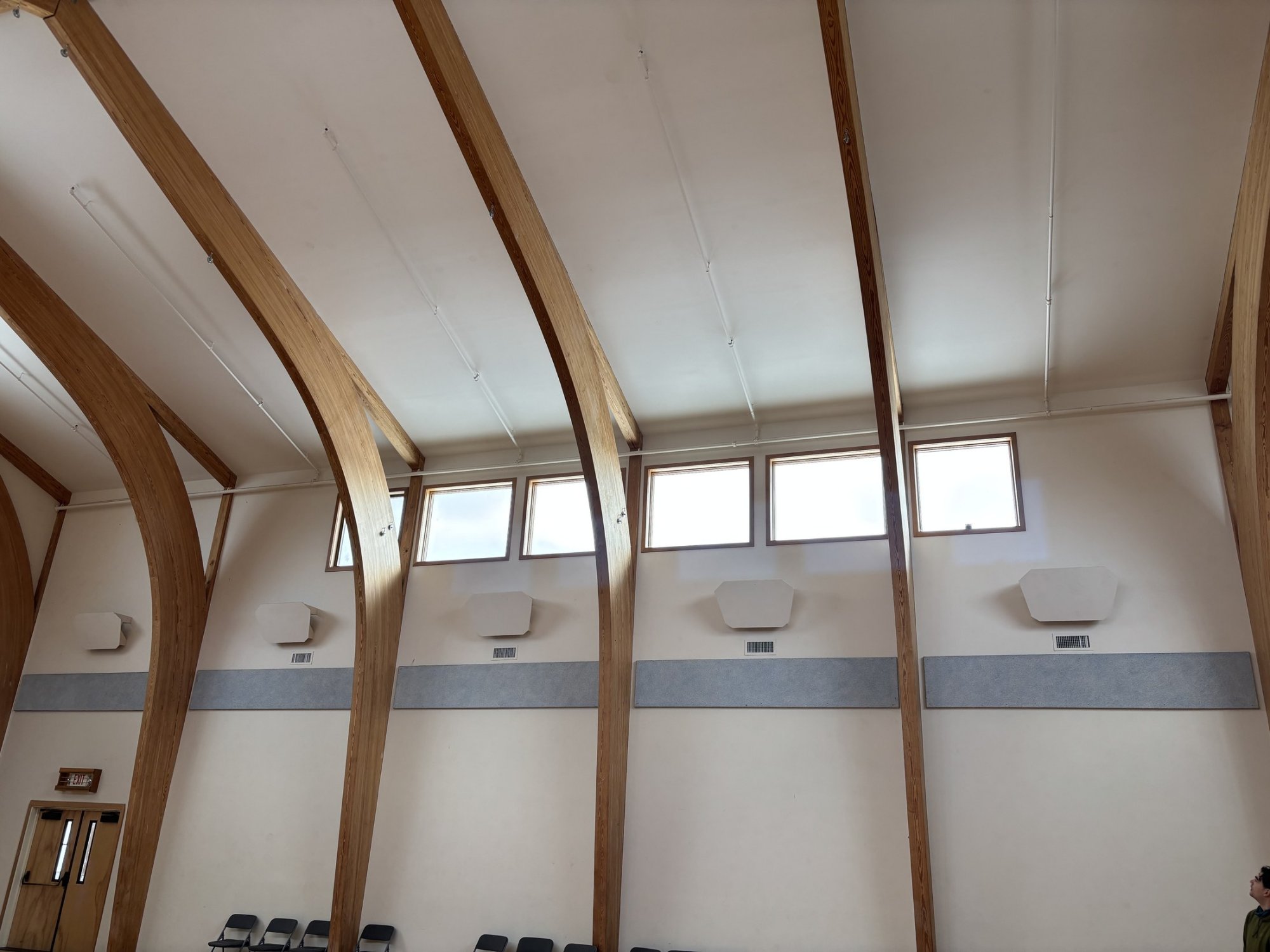Triform gymnasium in Hudson NY before acoustic treatment, showing bare gypsum ceiling and upper walls between glulam timber arches